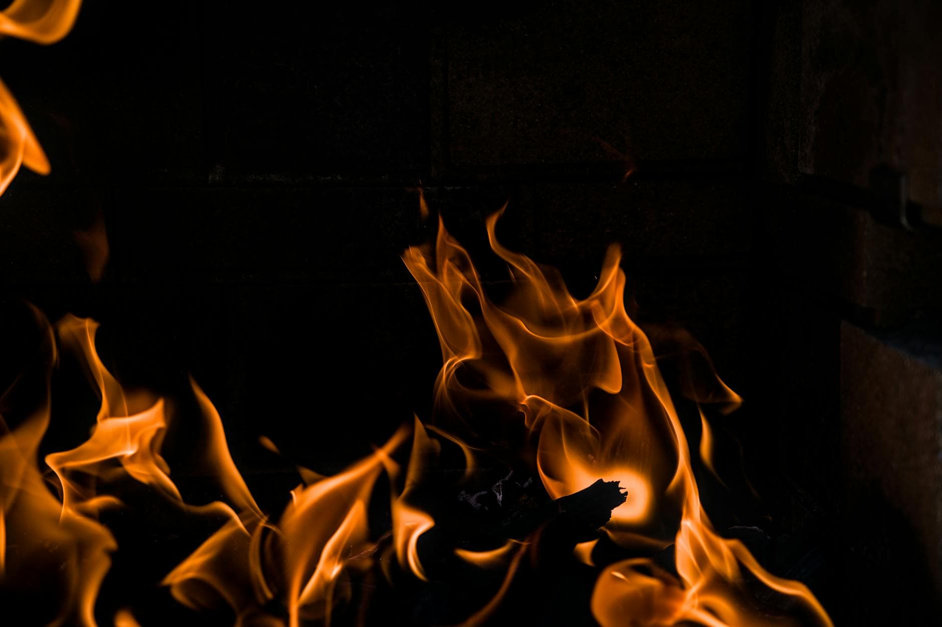 Capturing the vivid dance of orange flames in a dark fireplace setting.